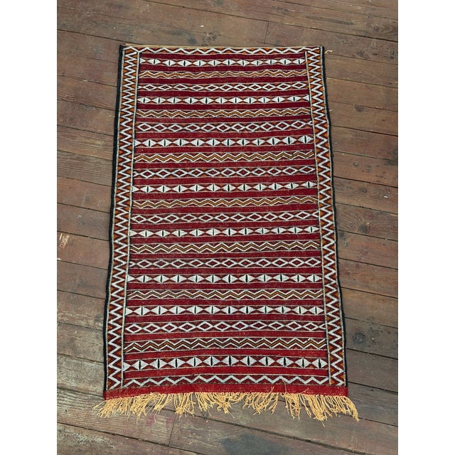 Hand knotted Moroccan Berber rug. Geometric pattern in deep red, white, black and orange. A distinct knotted wool rug that...