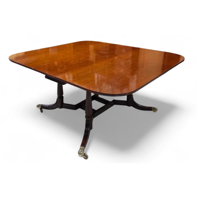 Featured is an elegant Baker Furniture Williamsburg Reproduction Mahogany Drop-Leaf Dining Table crafted in richly figured...