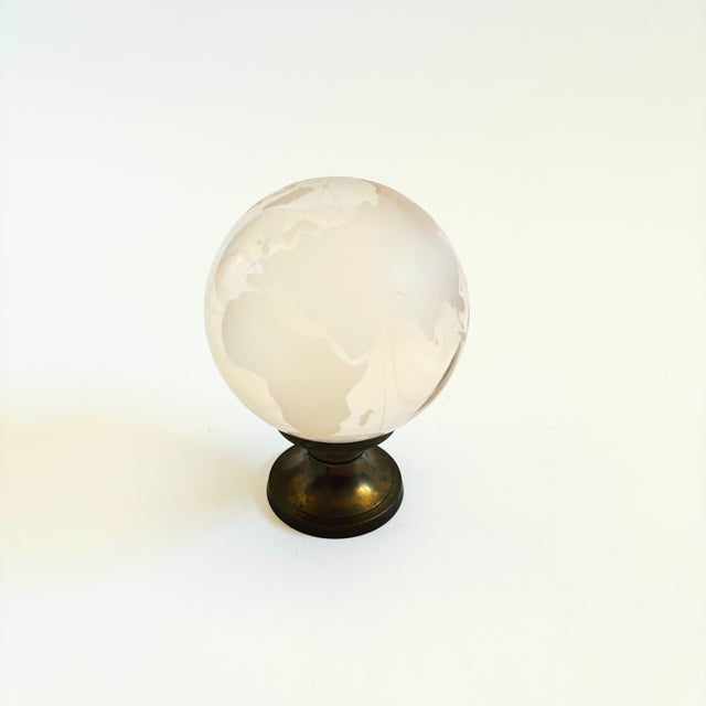 A vintage glass globe on a brass stand. Clear glass with frosted continents. Measures 3"Dia x 4.25"H