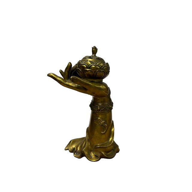 This striking brass incense burner is cast in the form of a graceful, elongated hand emerging from a draped sleeve,...