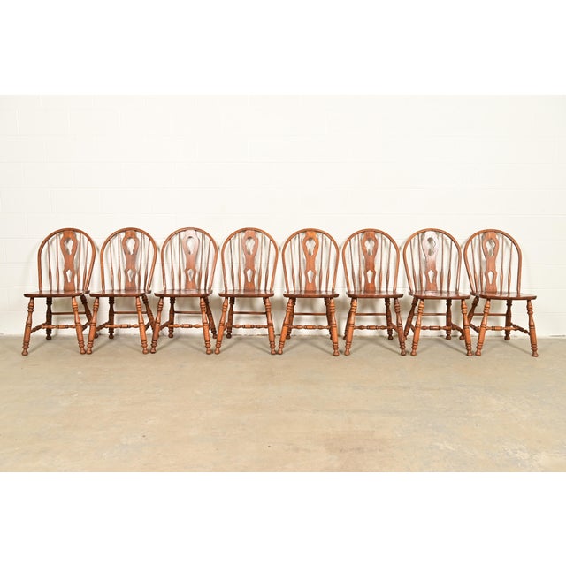 A gorgeous set of eight American Colonial style solid oak spindle back Windsor dining chairs In the manner of Ethan Allen...