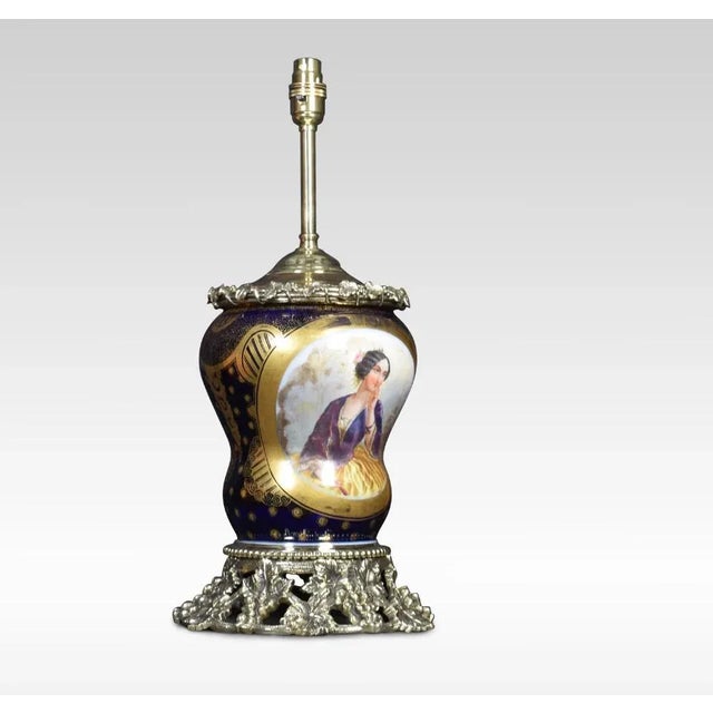 Sevres style table lamp, in cobalt blue with gold detail. The gilt bronze rim above central hand-painted panel depicting...