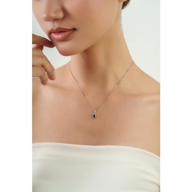 The Minimalist Oval 0.6 Ct Blue Sapphire Bezel-Set Solitaire Stackable Pendant features a beautiful 0.6-carat Blue...