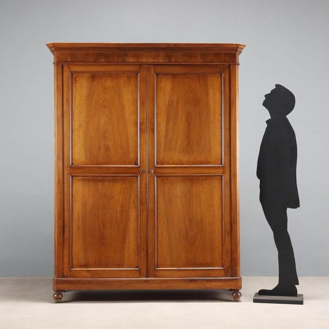 Walnut wardrobe. Front with two-part paneled doors, matching the sides, forty-five-degree uprights, and turned feet....