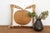 A large sun-disc medallion, hand-embroidered in a rich gold-tan thread, radiates from the center of this pillow — its...