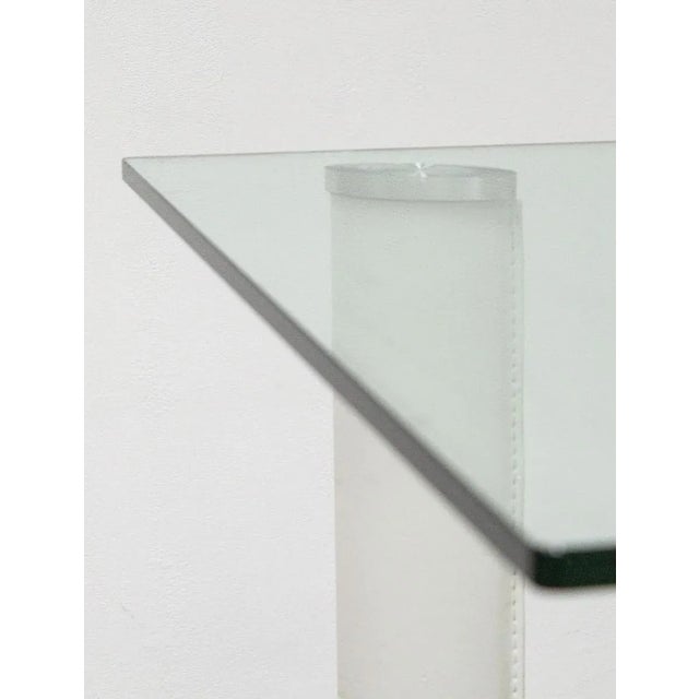 Tempered glass table with metal legs covered in leather The legs are arranged along the two diagonals, with a very...