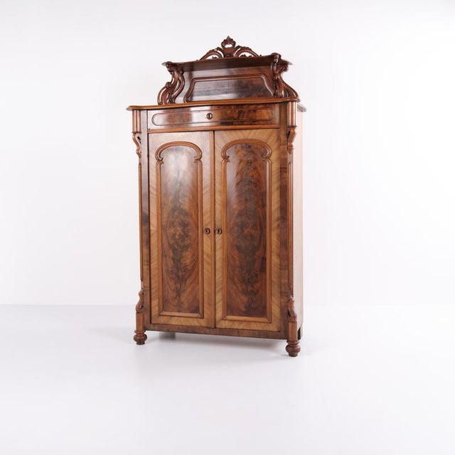 Antique mahogany cabinet from the 1880s with decorative carvings. Features doors and interior shelves, suitable for...