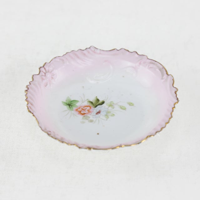 This enchanting Victorian-era dessert dish is crafted from fine porcelain, adorned with a blush pink border, scalloped...