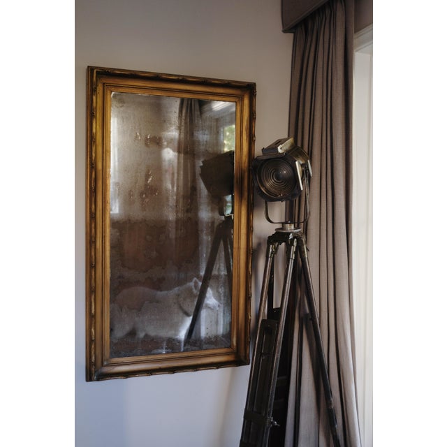 Striking vintage industrial spotlight mounted on an authentic military-style wood and metal tripod. Features an oversized...