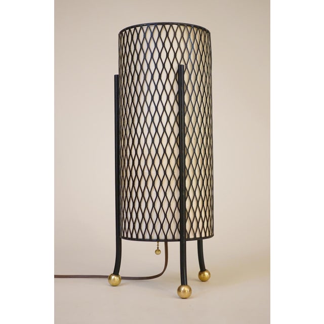 A minimal and futuristic atomic Modern "3-Legged" expanded metal cylinder fiberglass shade table lamp designed in the...