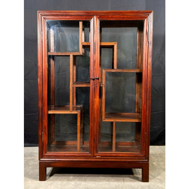 This Chinese rosewood display cabinet has two glazed front doors and glass panels on the sides and rear, with an...