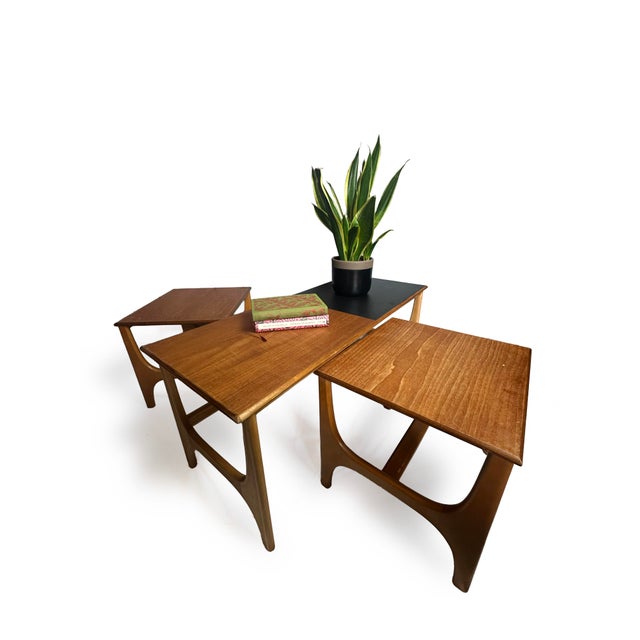 A trio of tables consisting of one large long coffee table and two square tables that sit neatly next to one another under...