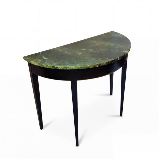 This is a midcentury Italian demilune console table with a faux marble top. The tapered legs and apron re black lacquer...