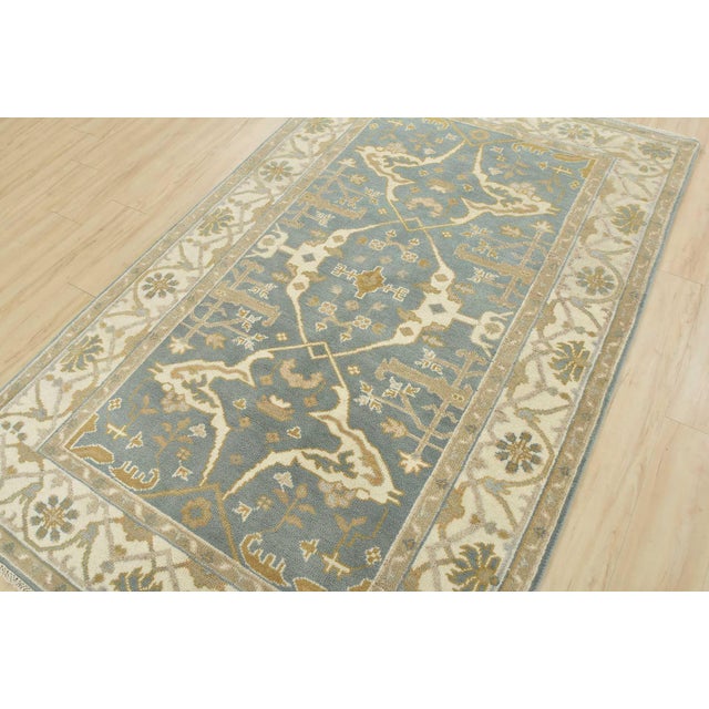 A modern tribal Oushak rug hand-knotted with an all-wool pile on a cotton foundation. This oriental rug features a central...