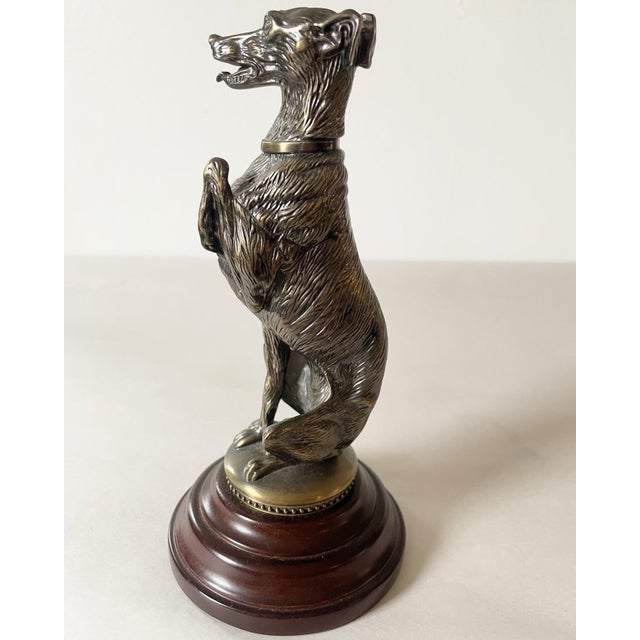 A handsome heavy bronze/brass figure of a whippet/greyhound with one paw up on a turned wood base. Such nice details!