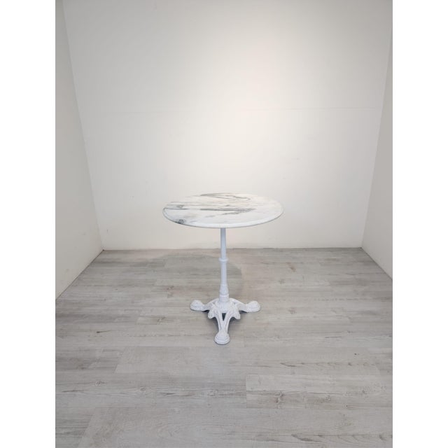 Marble coffee table with a whitewashed cast iron leg Round coffee table with a marble top on a painted cast iron leg. The...