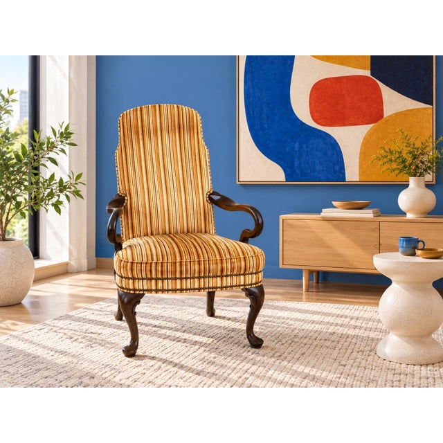 A vintage Queen Anne leg armchair featuring a vibrant orange and brown striped velvet upholstery with brass nailhead trim....