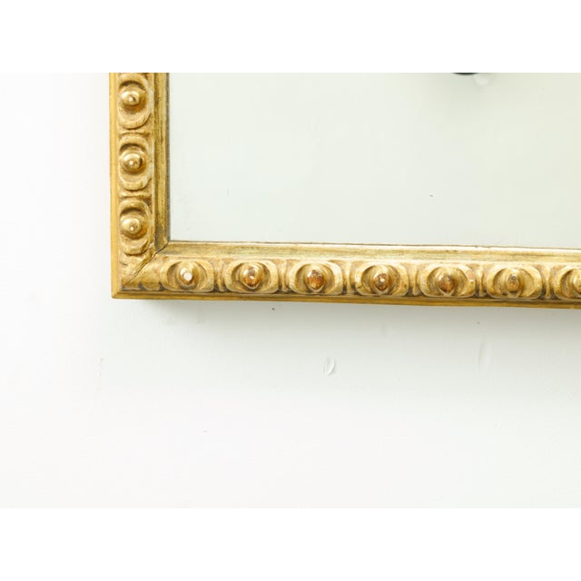 A French giltwood rectangular mirror from the mid-20th century, with carved ovoid motifs. Created in France during the...