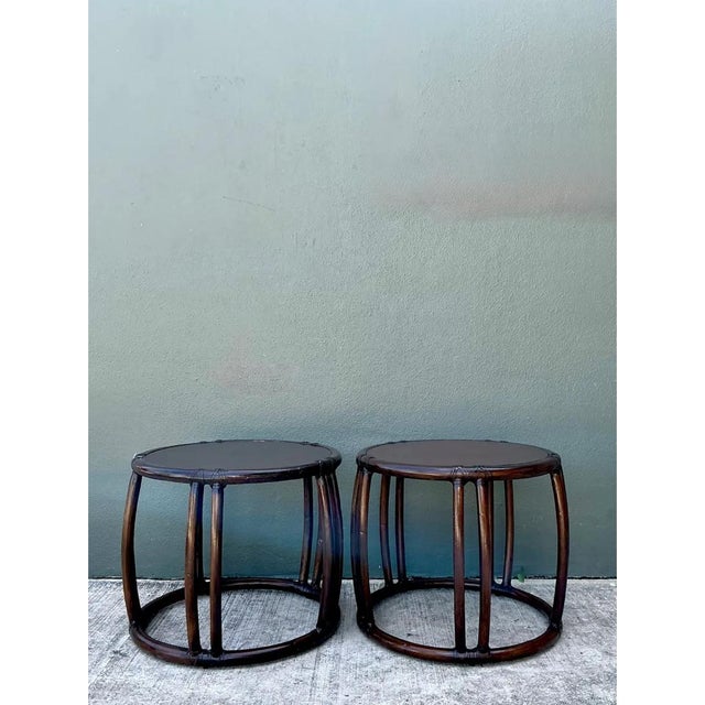 This pair of vintage McGuire rattan drum side tables presents a striking cylindrical silhouette, each piece constructed...