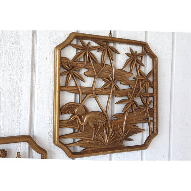 A vintage set of two decorative wood wall hangings, each depicting a different waterside scene. Original gold painted finish.