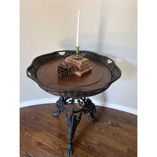 A striking Victorian Revival occasional table featuring an elaborately cast iron base supporting a generous leather-top...
