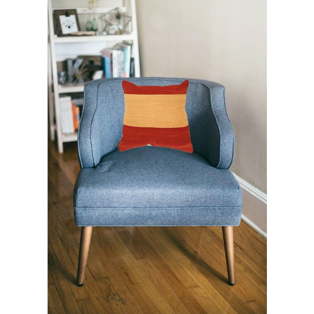 A one-of-a-kind handwoven wool kilim pillow featuring a bold red color-block with a golden center. Fully reversible —...