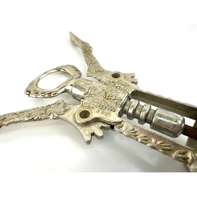 Vintage figural corkscrew featuring an ornate grapevine motif with detailed leaves and clustered grapes across the arms...