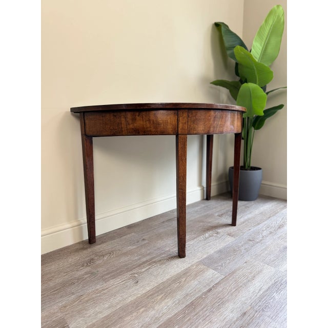 Beautiful simple antique large demi lune table standing upon four elegant square tapering legs.
