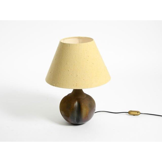 Beautiful 1960s German ceramic table lamp with an original fabric shade. Heavy, ornate ceramic base in dark brown, with a...