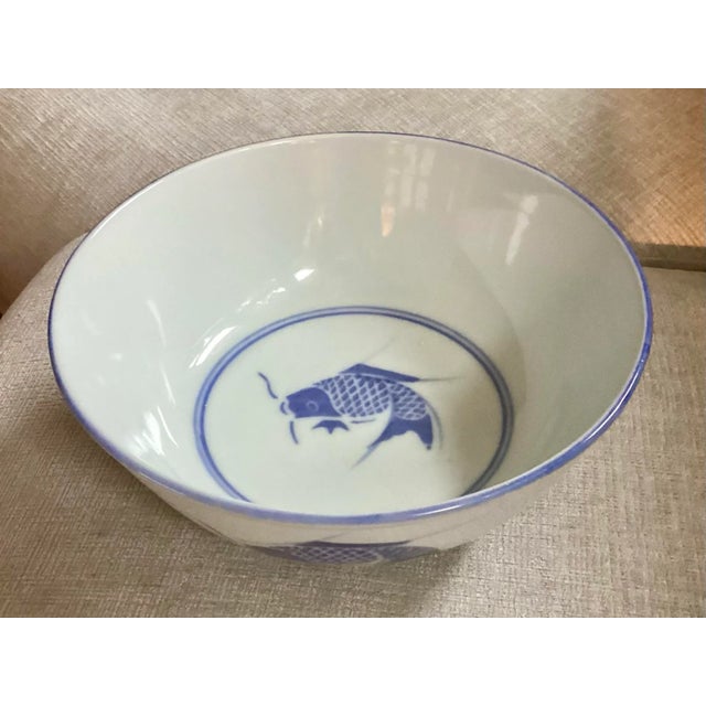Blue and white porcelain bowl from China, made in the 1980s. Koi fish adorn the exterior of the bowl while one lone fish...