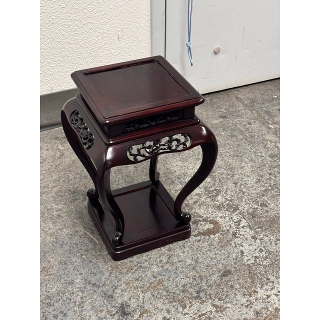 Design Plus Gallery presents a Chinese Pedestal Stand. It has a square top, open pierced apron, and flowing curved legs...