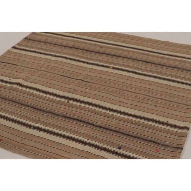 Handwoven in wool and originating circa 1950-1960, this 6x6 vintage Persian kilim and square rug is a rich tribal curation...