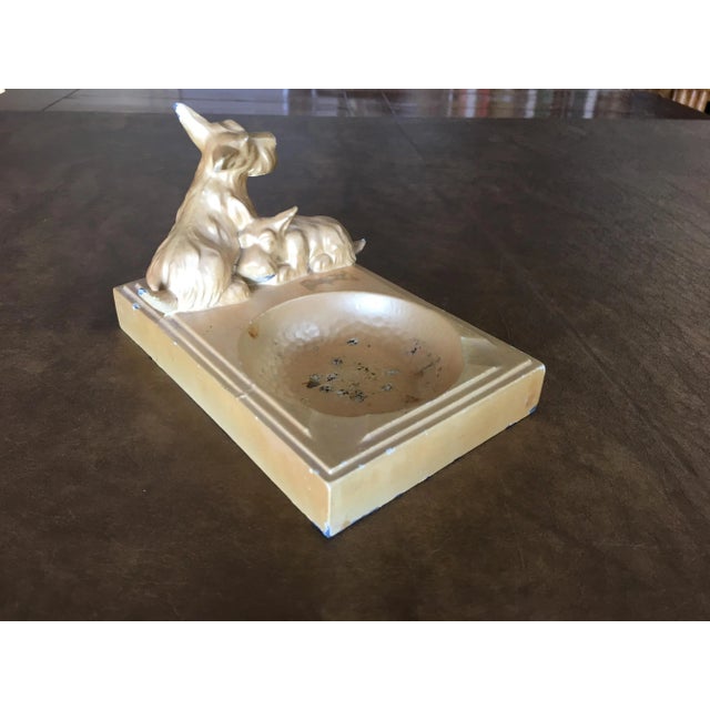 Art Deco enameled beige spelter metal terrier dog ashtray featuring cigarette holder and 2 sculptural dogs along the top....