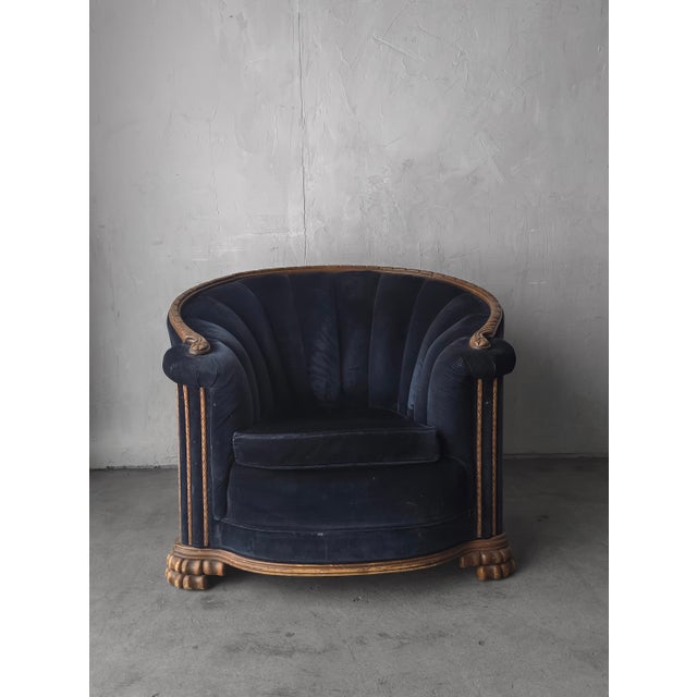 Elegant Art Deco club chair featuring a sculptural, barrel-form silhouette with channel-tufted navy velvet wood detailing...