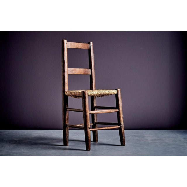French rustic ladder-back chair, early 20th century. Hand-crafted in solid wood with a woven straw seat, this vernacular...