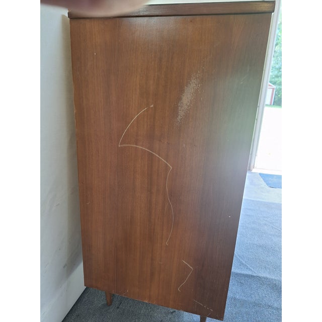 This Dixie chest is made of wood, walnut, and veneer. It's an excellent example of the Mid Century Modern furniture style....