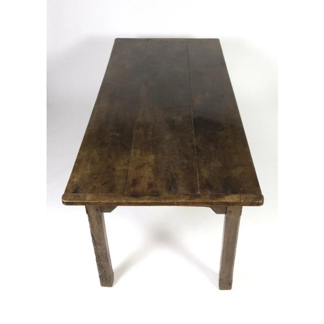 A charming and rustic English fruitwood farm table; single drawer on the side with a simple patinated brass pull, circa...