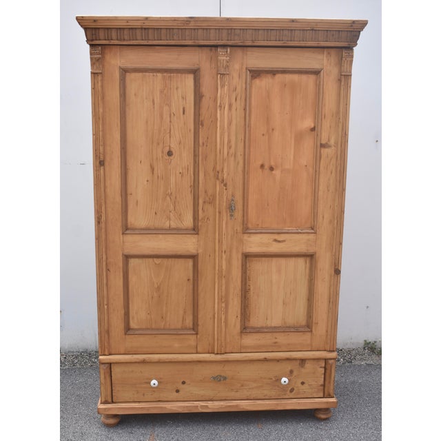 The bold crown of this typical Central European pine armoire comprises a pine ogee molding above a strip of hardwood...