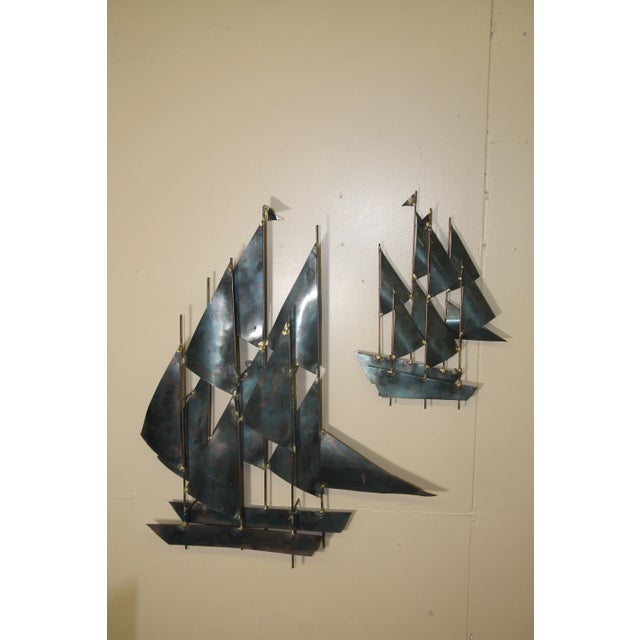 Great pair of metal sailboat wall sculpture in the manner of Curtis Jere. Large ship is 26W x 6D x 32H, small ship is...