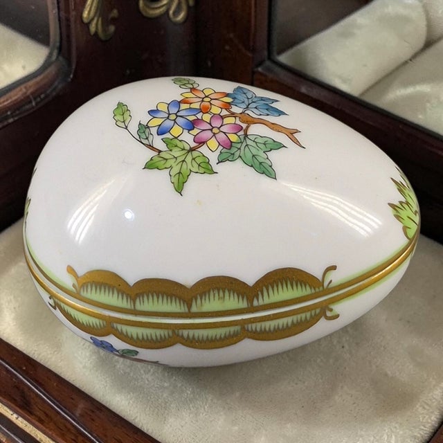 The Herend Queen Victoria Pattern Fine Porcelain Hand Painted Floral Egg Trinket Box is a beautifully crafted decorative...