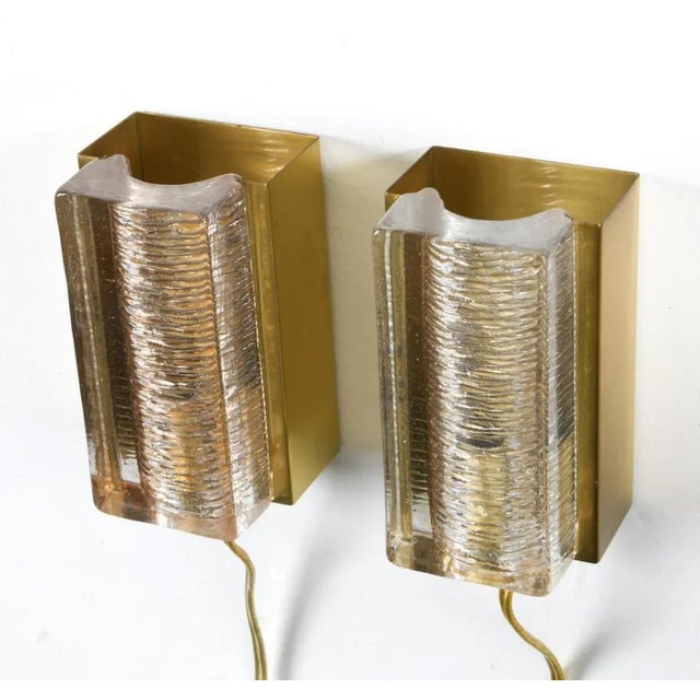 A pair of 1960'a wall sconces crafted by the Danish manufacturer Vitrika. Brass wires wrap around the plate holding the...