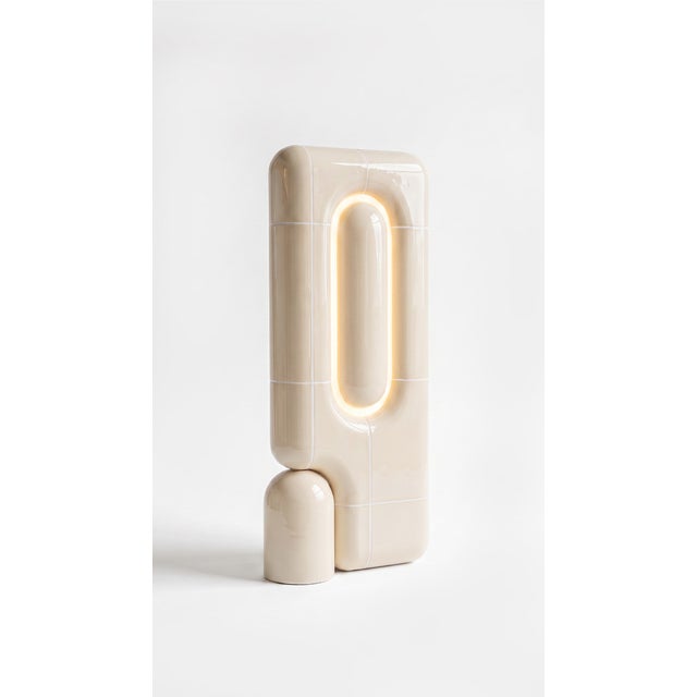 The vertical one. Where the rest of the collection sits low and grounded, this table lamp rises in a slim column of curved...