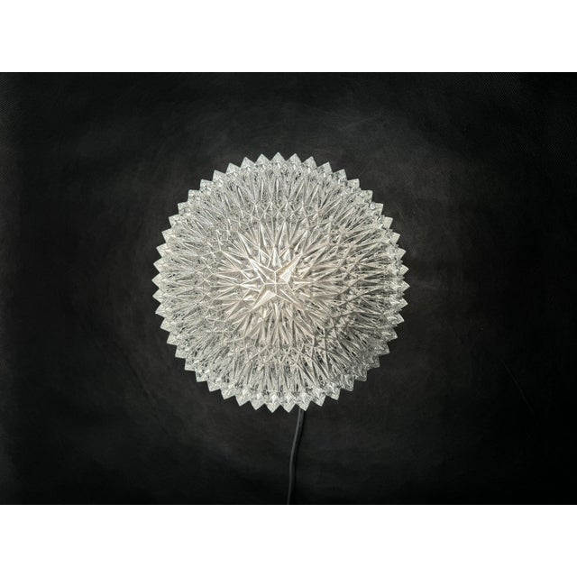 Decorative ceiling flush mount made of thick pressed glass with a bold geometric pattern, set in a silver-toned metal...