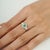 Diamond-studded regal natural emerald cocktail ring featuring a 0.56-carat oval-cut emerald at the center, framed by an...