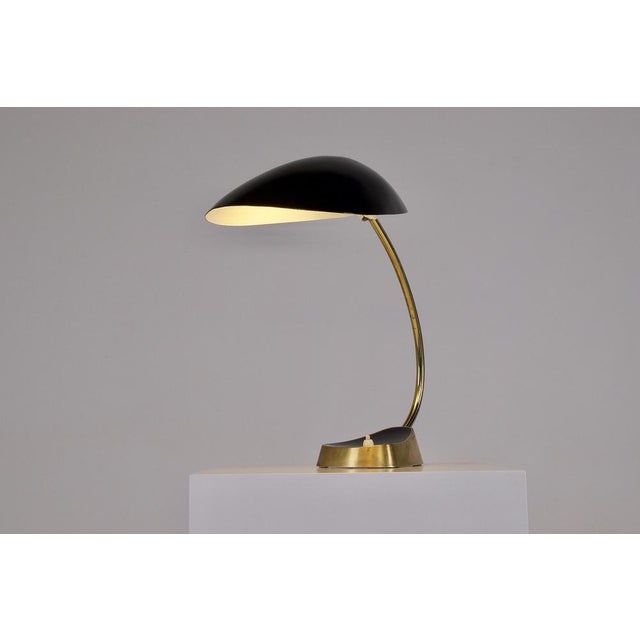 Rare and very elegant modernist lamp in solid brass, with adjustable reflector in black lacquered aluminum. Its reflector...