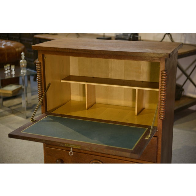 A robust oak secretary desk in the style of 1950s French furniture. The drop-front upper section forms a writing surface,...