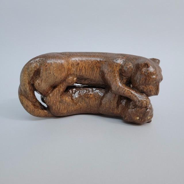 An antique Asian decorative sculpture depicting two intertwined panthers, hand-carved from a single block of dense...
