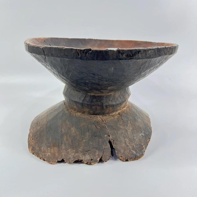 This traditional Ugandan wooden stool is hand-carved from a single block of hardwood and features a shallow concave seat...