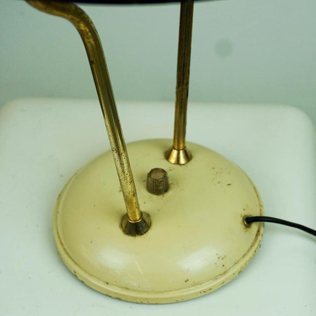This charming design desk lamp has been manufactured in Italy in the 1950s. The structure is made of brass with cream...