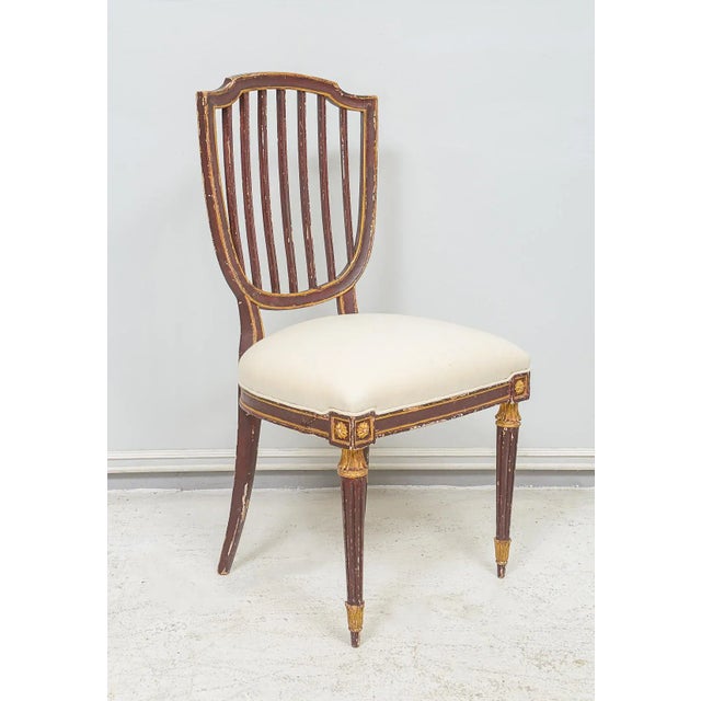 Set of Eight Dining Chairs in the Neoclassic Manner - chairs are hand-painted and gilded with fluted legs and shield-backs...